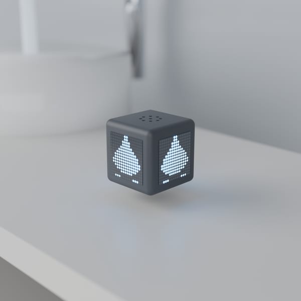 Lo stesso cubo sul piano di un bagno: le facce mostrano una goccia d'acqua. Dietro, fuori fuoco, il lavabo e il rubinetto aperto.