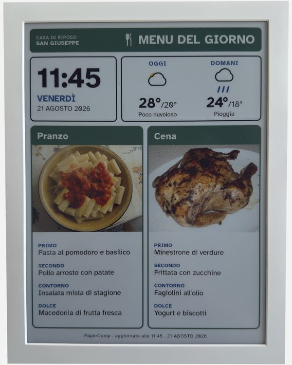 A 13.3-inch eInk label photographed head on: it shows the day's menu, lunch and dinner side by side, with a photograph of a dish for each.