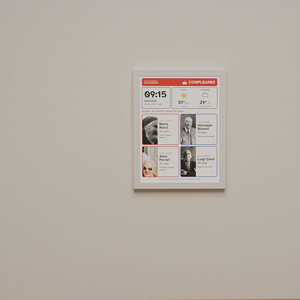 A corridor: an eInk label above a sideboard shows this month's birthdays, with the name and photograph of each resident.